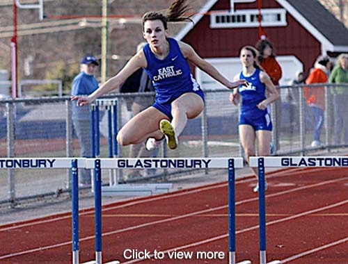 Track and field team member jumps over a barrier