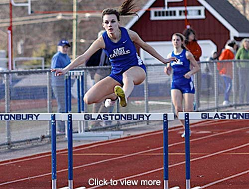 Track and feels team member jumps over a barrier