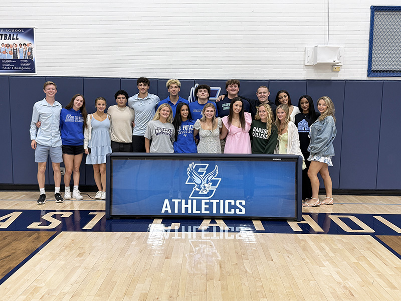 Group of happy student athletes at a college signing table