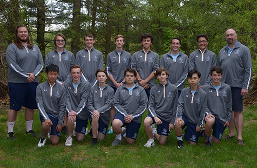 Boys tennis team posing together on grass
