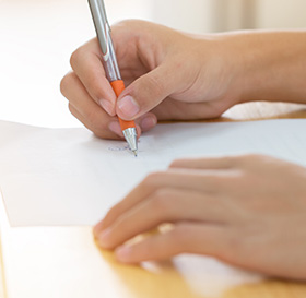 hands with pen writing on paper